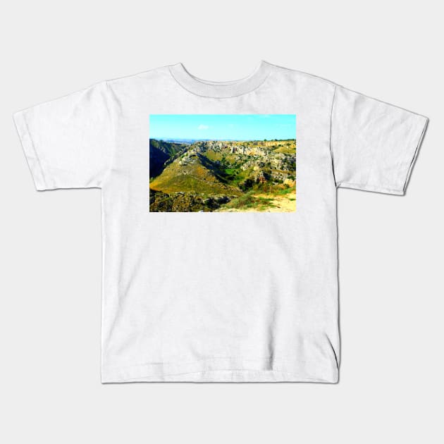 Rocky canyon partly covered with green grass and randomly placed shrubs near Matera Kids T-Shirt by KristinaDrozd